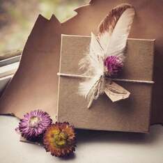 Picture of a customers decorative packaging using dried flowers and feathers from Running Bug Farm.