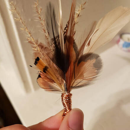 Picture of a handmade feather boutonnier using real feathers from running bug farm.