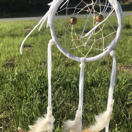 Picture of a dream catcher made by a customer of Running Bug Farm using cruelty free buff laced polish rooster feathers.